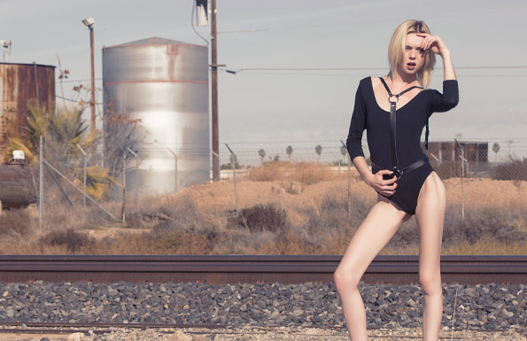 Woman in black bodysuit by railway tracks