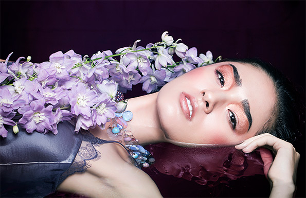 Young woman lying in water with purple flowers